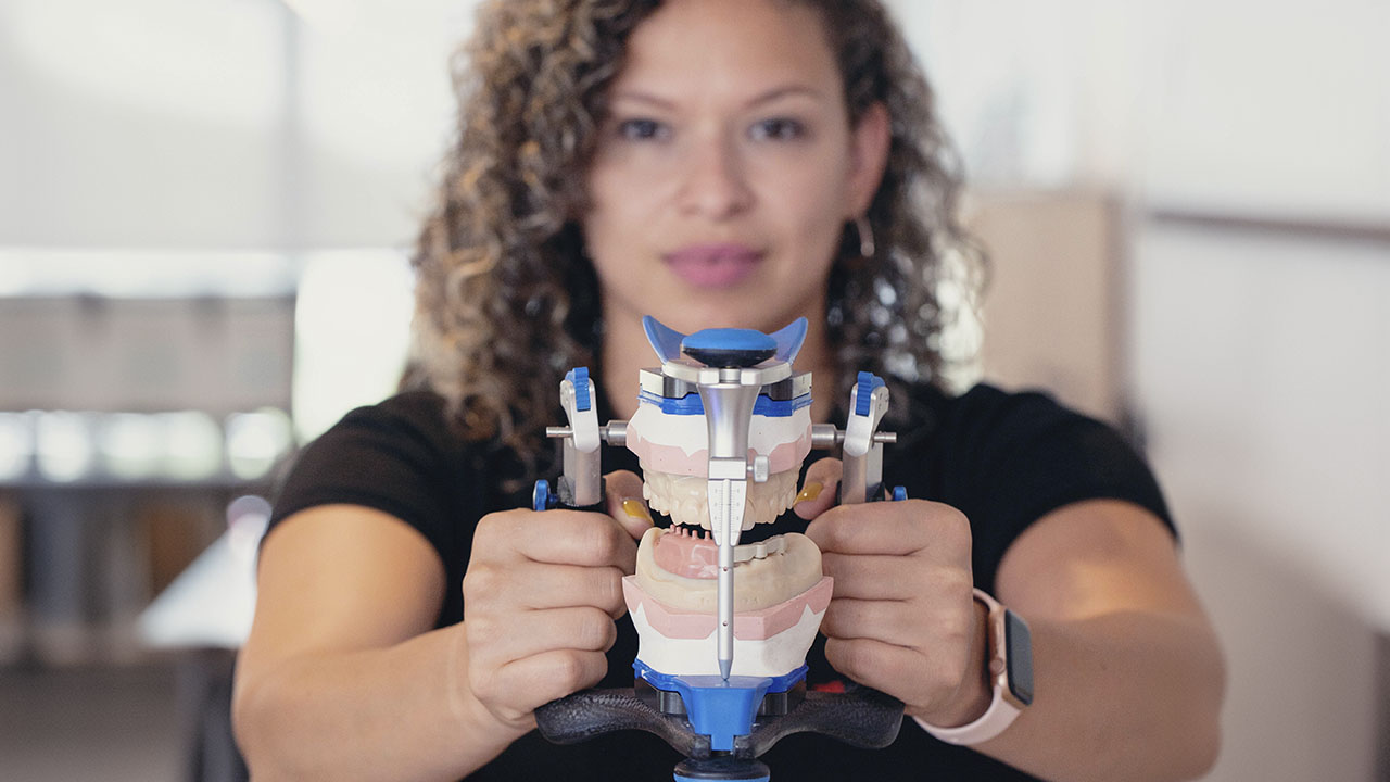 Jeisy Arca Jiménez, prótesica dental, mirando a la cámara y sujetando un articulador.